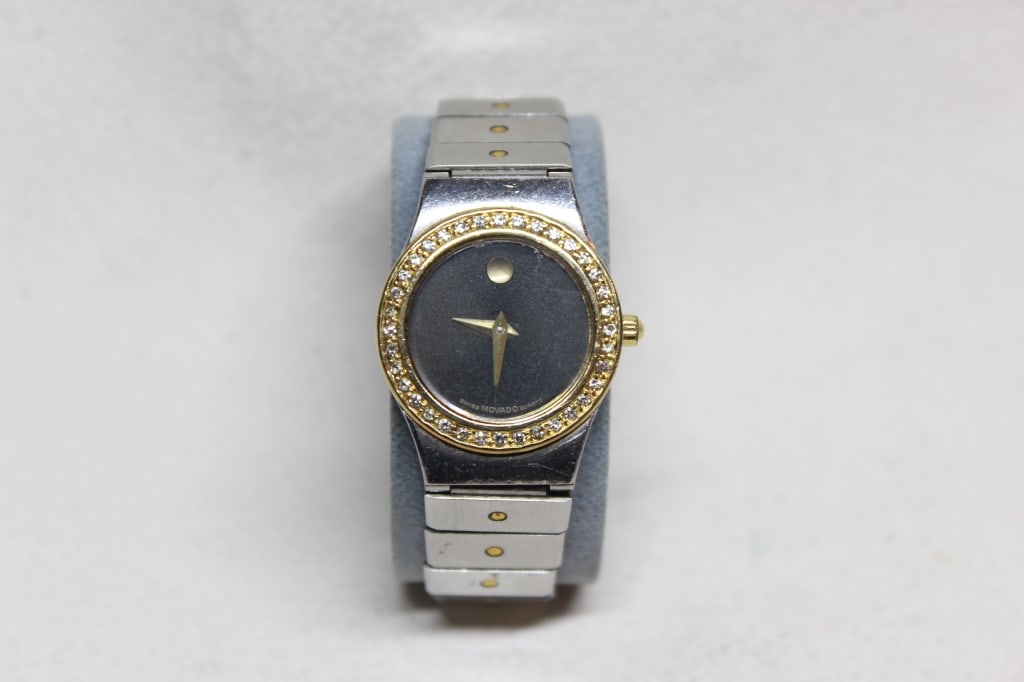 Movado Museum Diamond Bezel watch: This specific model features a two-tone aesthetic with a stainless steel case and bracelet accented by a gold-plated diamond-set bezel.A stainless steel link bracelet with gold-tone "dot" accents on