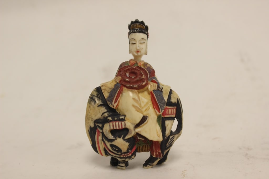 Vintage Chinese Polychrome carved Bone figurine: Dimension : A serene female figure sits sidesaddle atop the animal. She wears traditional courtly robes and an elaborate, high-tiered crown or tiara over her dark hair. In her hands, she prominently