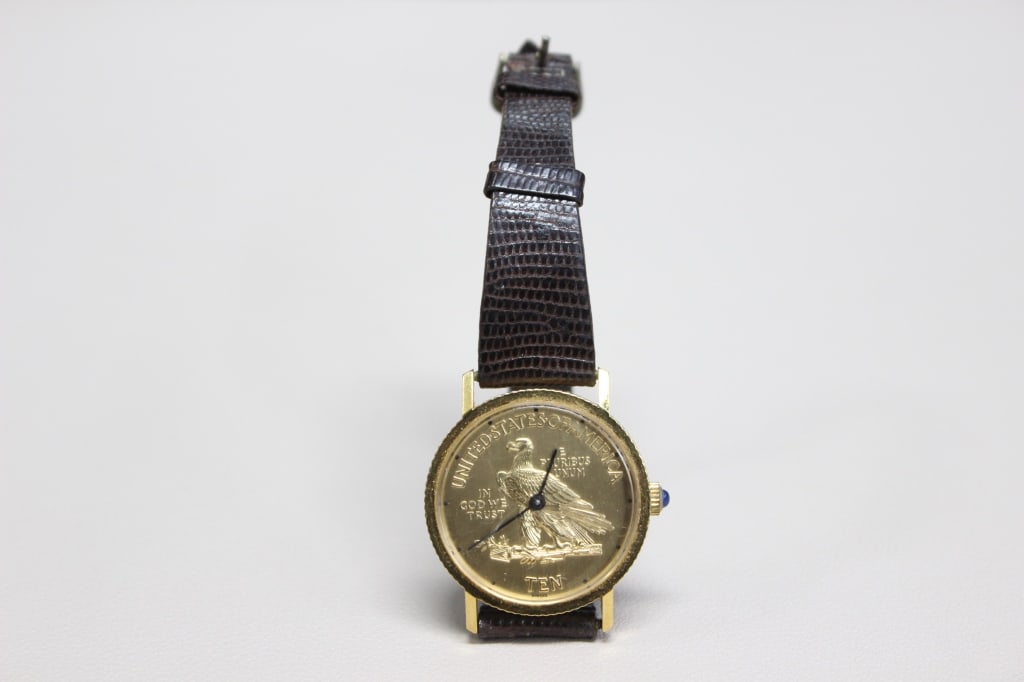 Vintage American Eagle TEN Dollar Coin watch: Dial features the reverse side of a U.S. $10 "Indian Head Eagle" coin, depicting an eagle standing on a bundle of arrows and an olive branch. Crown: Often features a blue cabochon tip, a