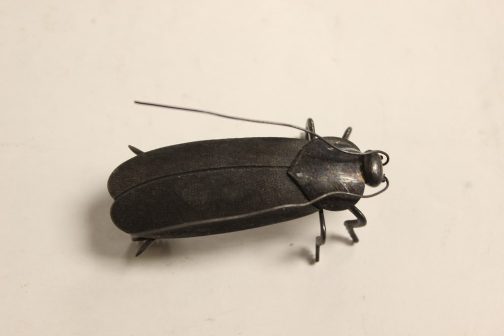 Japanese articulated metal cockroach: Japanese articulated metal cockroach Dimension : 2"L . The insect features long, thin metal wire antennae, multi-jointed legs with meticulously filed spikes, and a layered, matte dark-iron or