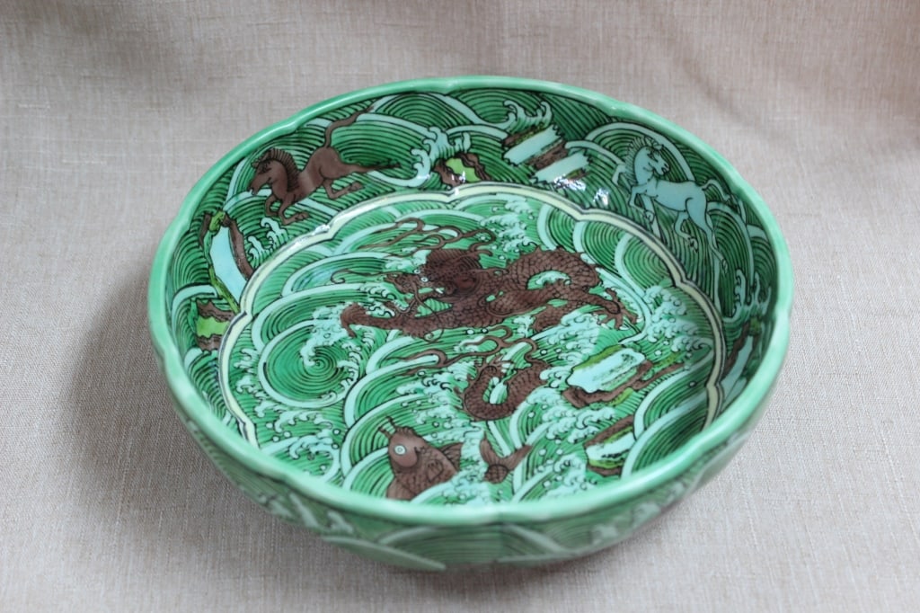 Chinese Glazed Porcelain Bowl,Mark: Dimension:7"W. The center of the interior basin features a dynamic aubergine/brown-enameled dragon thrashing amidst powerful, stylized green and white sea waves. Along the inner curved walls, multiple