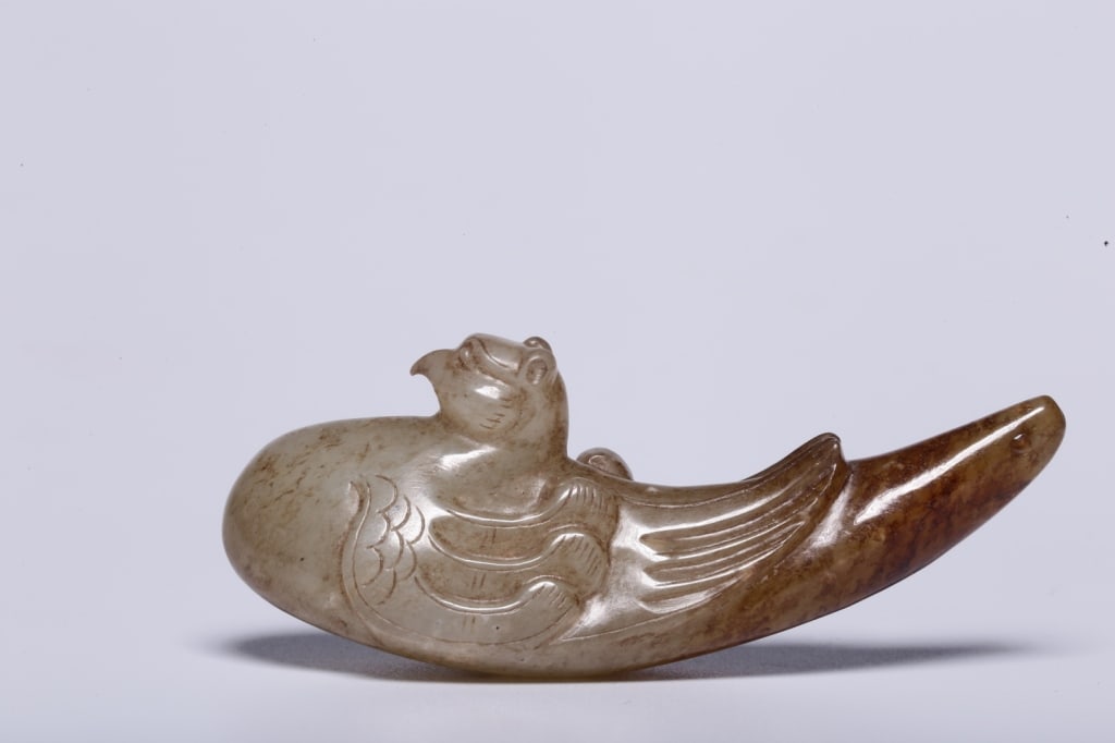 Chinese Carved Nephrite jade of a mythical Bird: Dimension: 6.5cm L x 2.2 cm x 2.6cm,weight is 32g. The bird is depicted in a recumbent or nesting position with its head raised high, showcasing a hooked beak and large stylized round eyes.