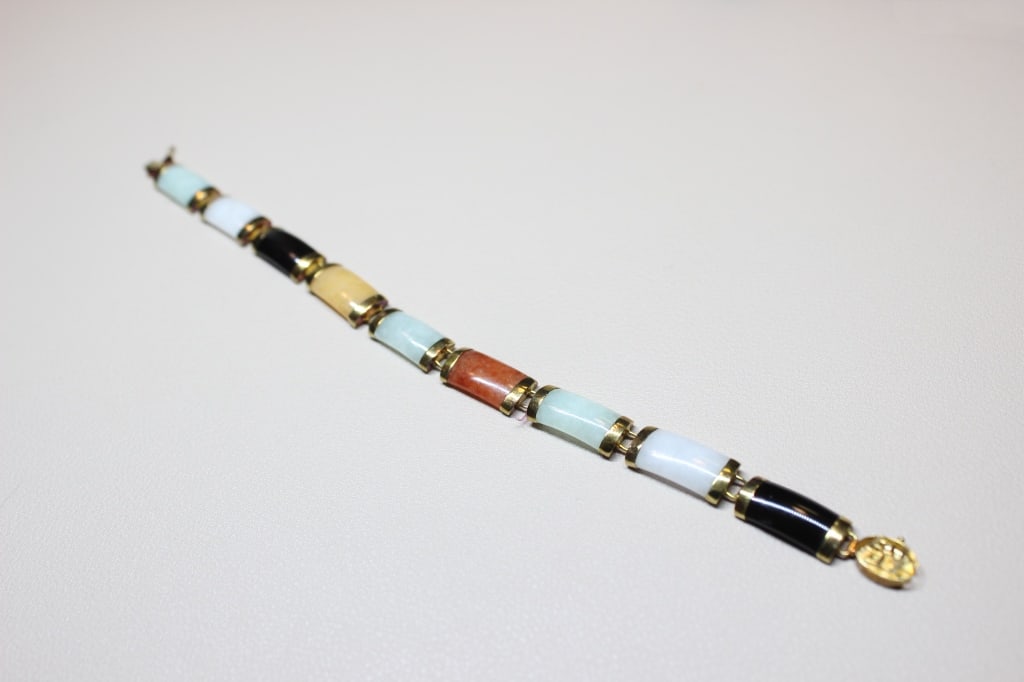 Multi-colored Jade link bracelet set in 14K Gold: The stones include a variety of hues such as green, white, black, russet/orange, light blue/celadon, yellow, and sometimes purple. Each stone segment is capped with gold on both ends and linked to the