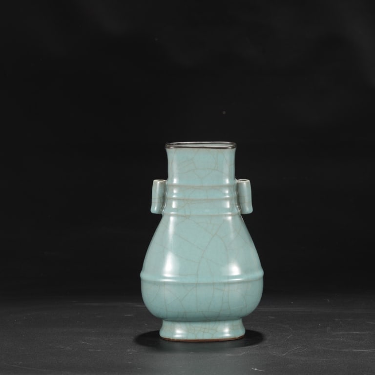 Chinese celadon-glazed archaistic vase: Dimension: 24cm H x 15cm w . The vessel features a flattened, pear-shaped body rising to a stout neck flanked by two vertical tubular arrow handles (guaner), a shape inspired by ancient bronze hu vess