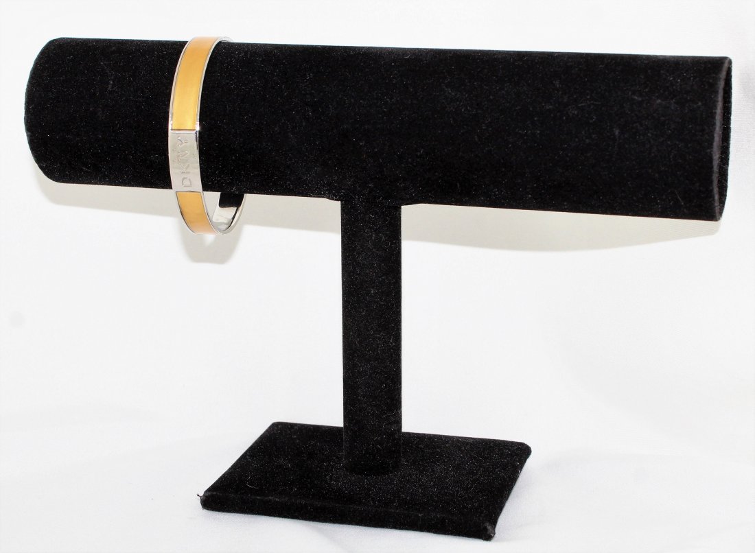 DKNY Bangle Bracelet: DKNY Gold Enamel on Silver Bangle Bracelet with DKNY logo at the front center. The exterior width is 2 5/8", the interior width is 2 1/2" and the bangle width is 3/8". The interior length is 7 3/4".