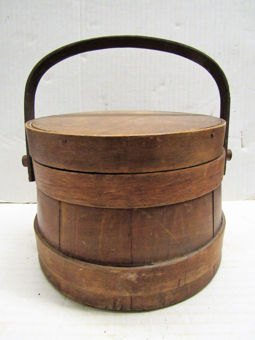 Primative small lap banded firkin: Antique firkin was hand made from pine, 6.5" in diameter, 5" tall to lid. It has a swing oak handle and top edge is wooden pegged to center. It has nice patina.