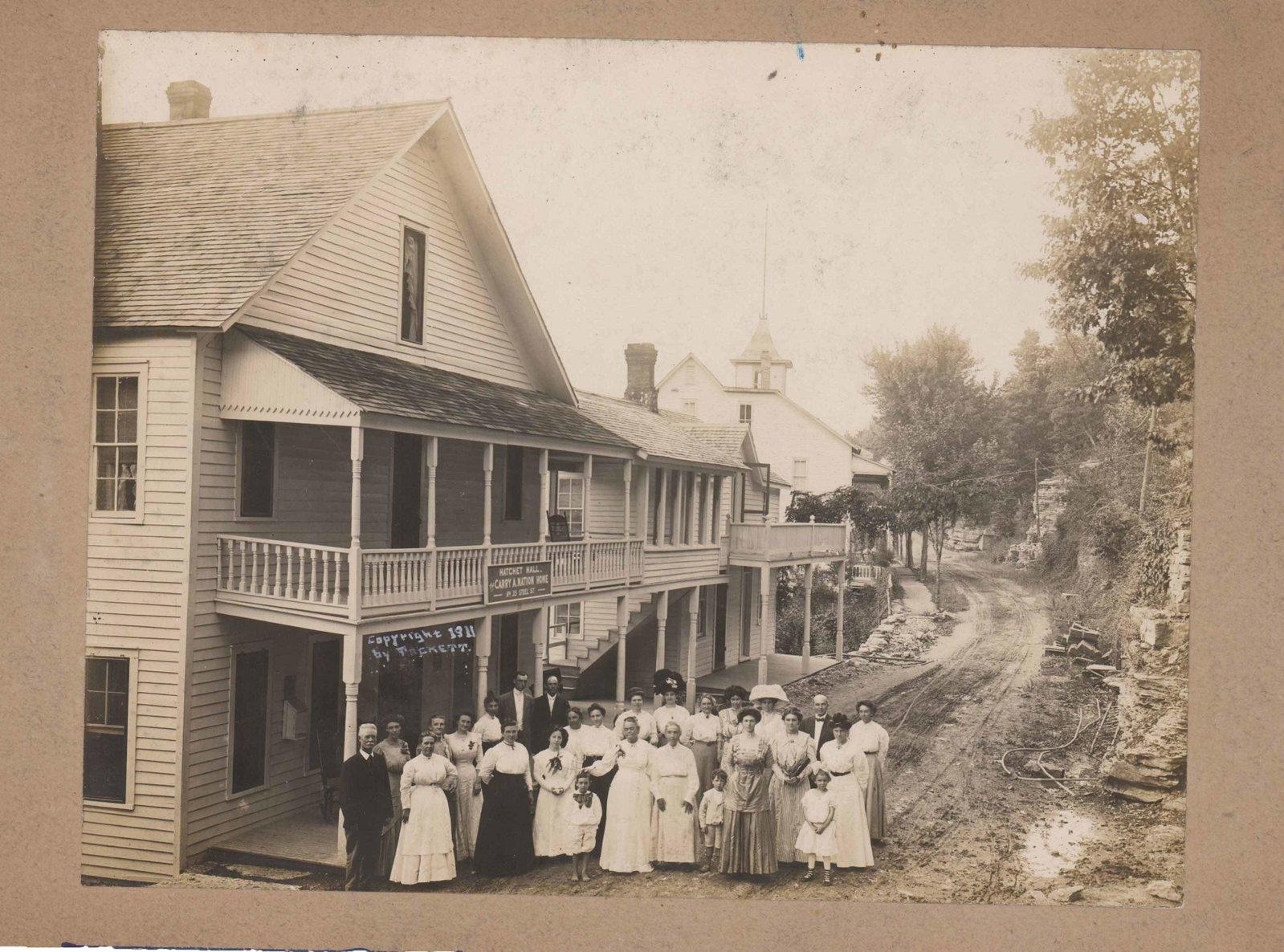 Carrie Nation Vivid Photo Standing in Front of Hatchet Hall: Excellent Carrie Nation Photo Standing in Front of Hatchet Hall A sepia-toned photograph of Nation posed with a large group of people in front of Hatchet Hall in Eureka Springs, Arkansas. Measuring 9.