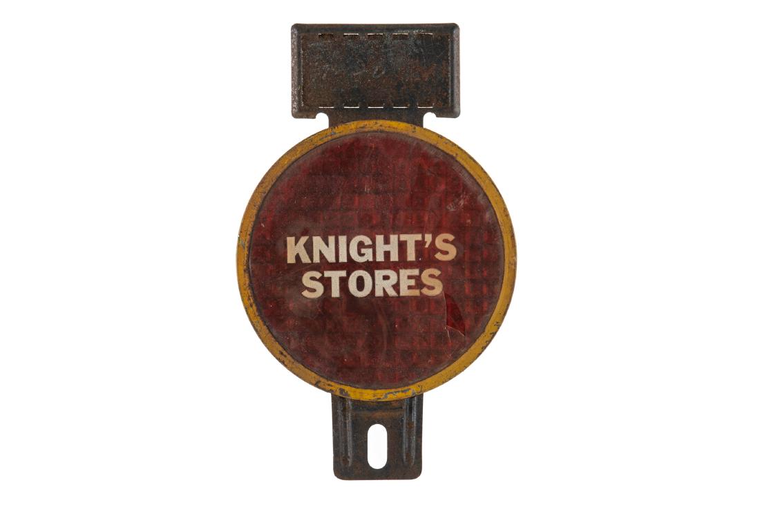 Knight's Stores License Plate Topper: Celluloid over tin with reflective backing. Shows areas of discoloration and creasing in the celluloid. Measures: 6.5"X4" Rating: 6.75 Est: $50-$150