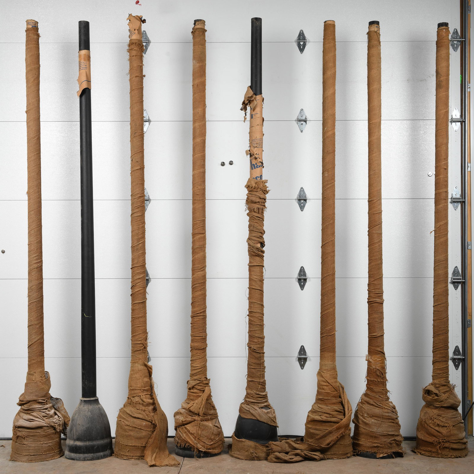 Lot Of Eight Light Poles: NOS aluminum light poles wrapped in burlap. Measures: 120"X12" Est: $600-$1,000