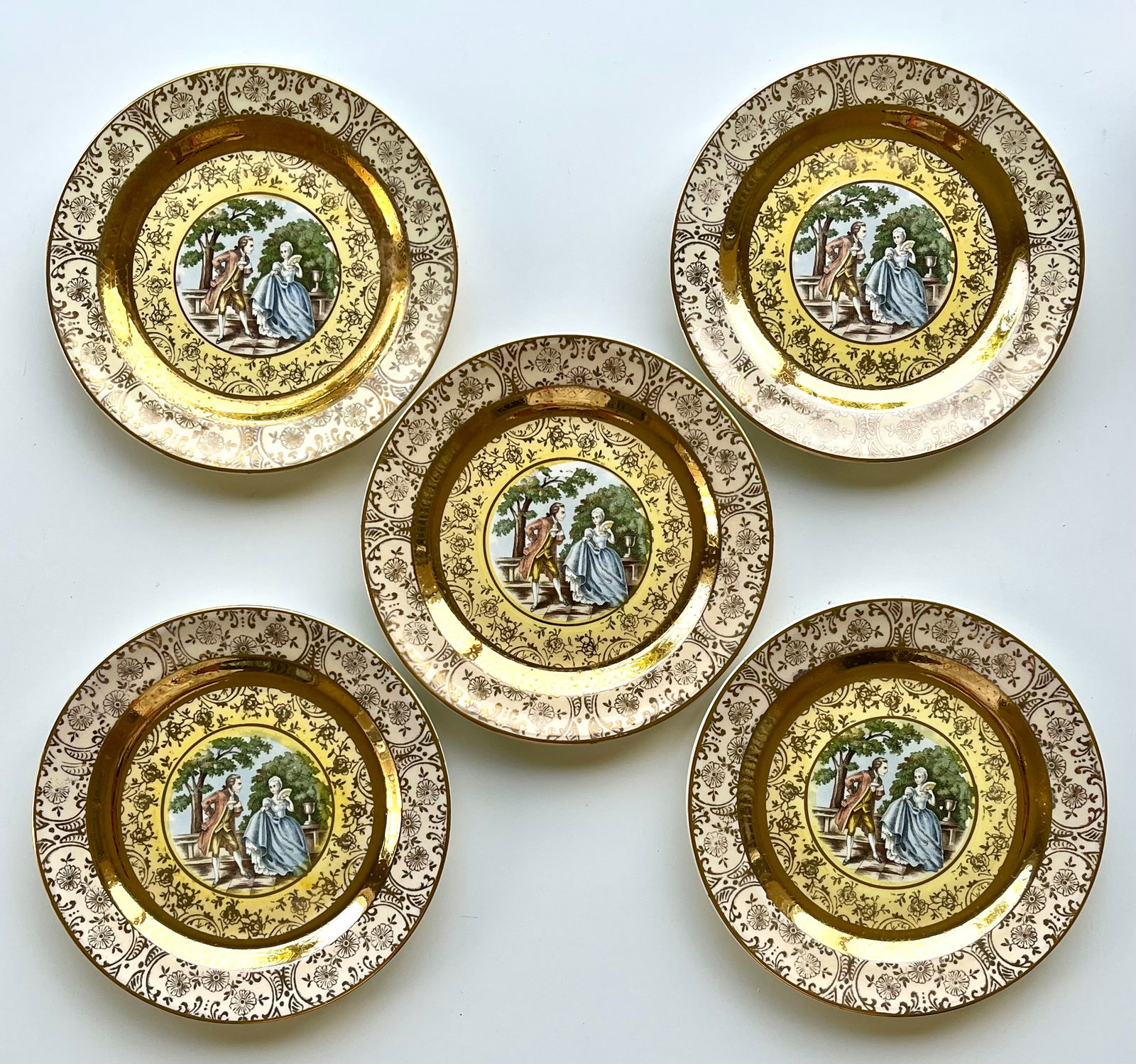 Victorian Style Porcelain Plates Set of 5 – 22K Gold Trim 6 inches Bromley: Set of 5 vintage Bromley decorative plates featuring a romantic courting couple scene in the center. Elegant ornate border with rich 22K gold trim. Marked on back: Bromley – Decorated – 22 Karat G
