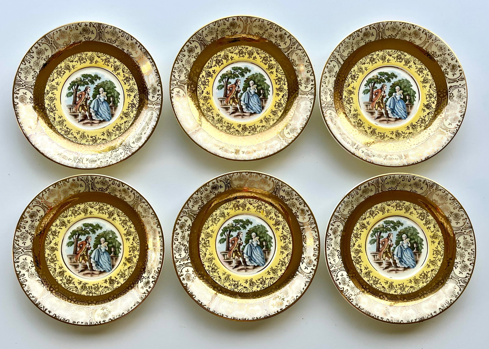 Victorian Style Porcelain Plates Set of 6 – 22K Gold Trim 6.5 in Bromley: Set of 6 vintage Bromley decorative plates featuring a romantic courting couple scene in the center. Elegant ornate border with rich 22K gold trim. Marked on back: Bromley – Decorated – 22 Karat