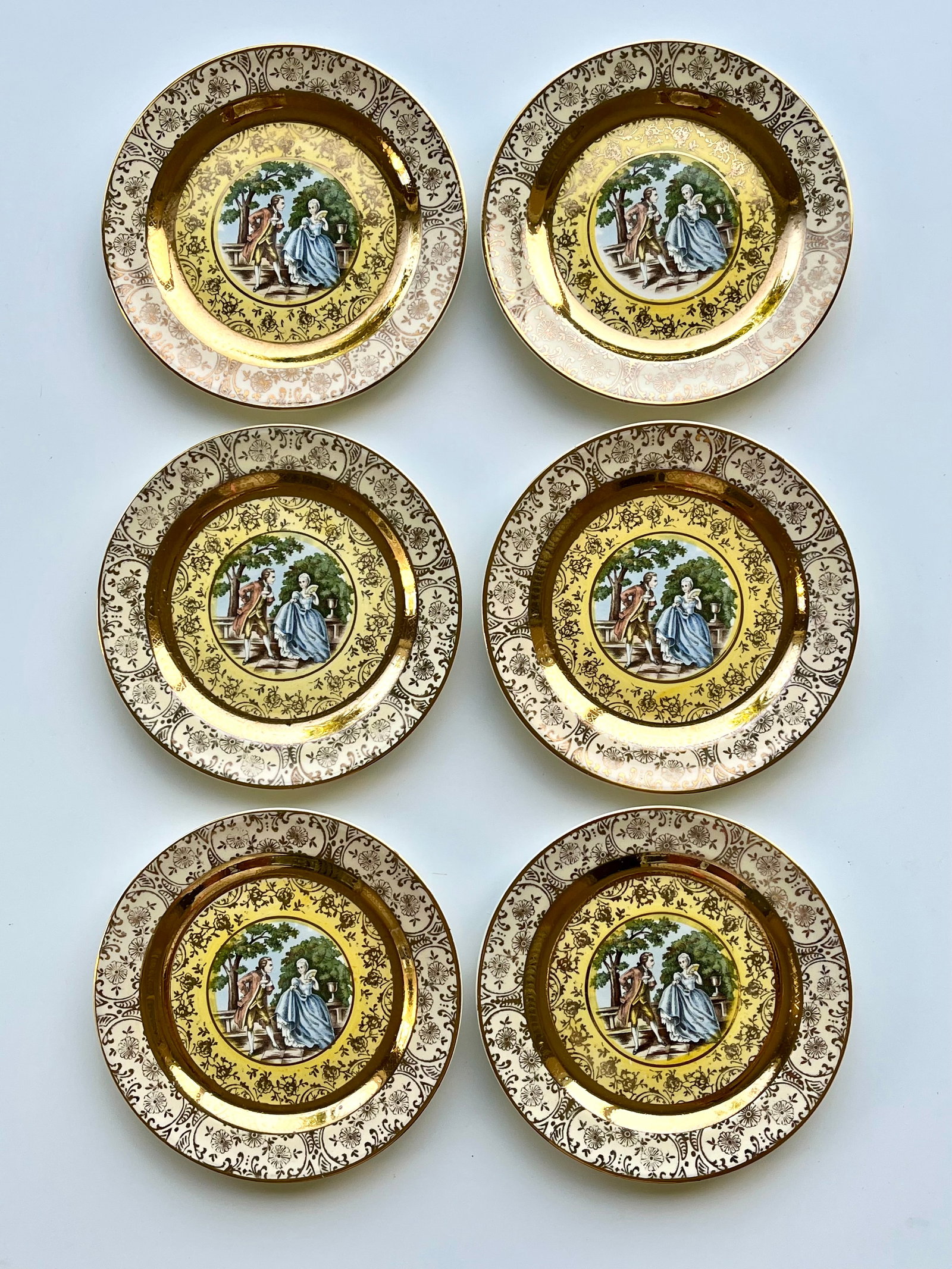 Victorian Style Porcelain Plates Set of 6 – 22K Gold Trim 6.5 in Bromley: Set of 6 vintage Bromley decorative plates featuring a romantic courting couple scene in the center. Elegant ornate border with rich 22K gold trim. Marked on back: Bromley – Decorated – 22 Karat