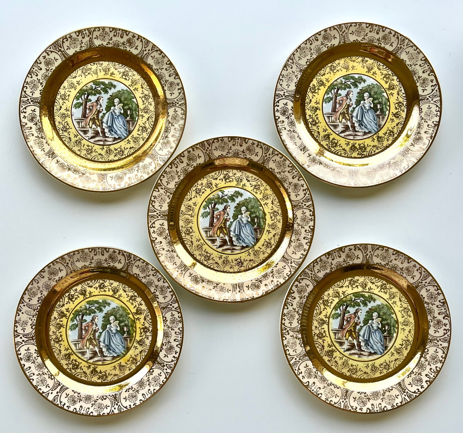Victorian Style Porcelain Plates Set of 5 – 22K Gold Trim 6 inches Bromley: Set of 5 vintage Bromley decorative plates featuring a romantic courting couple scene in the center. Elegant ornate border with rich 22K gold trim. Marked on back: Bromley – Decorated – 22 Karat