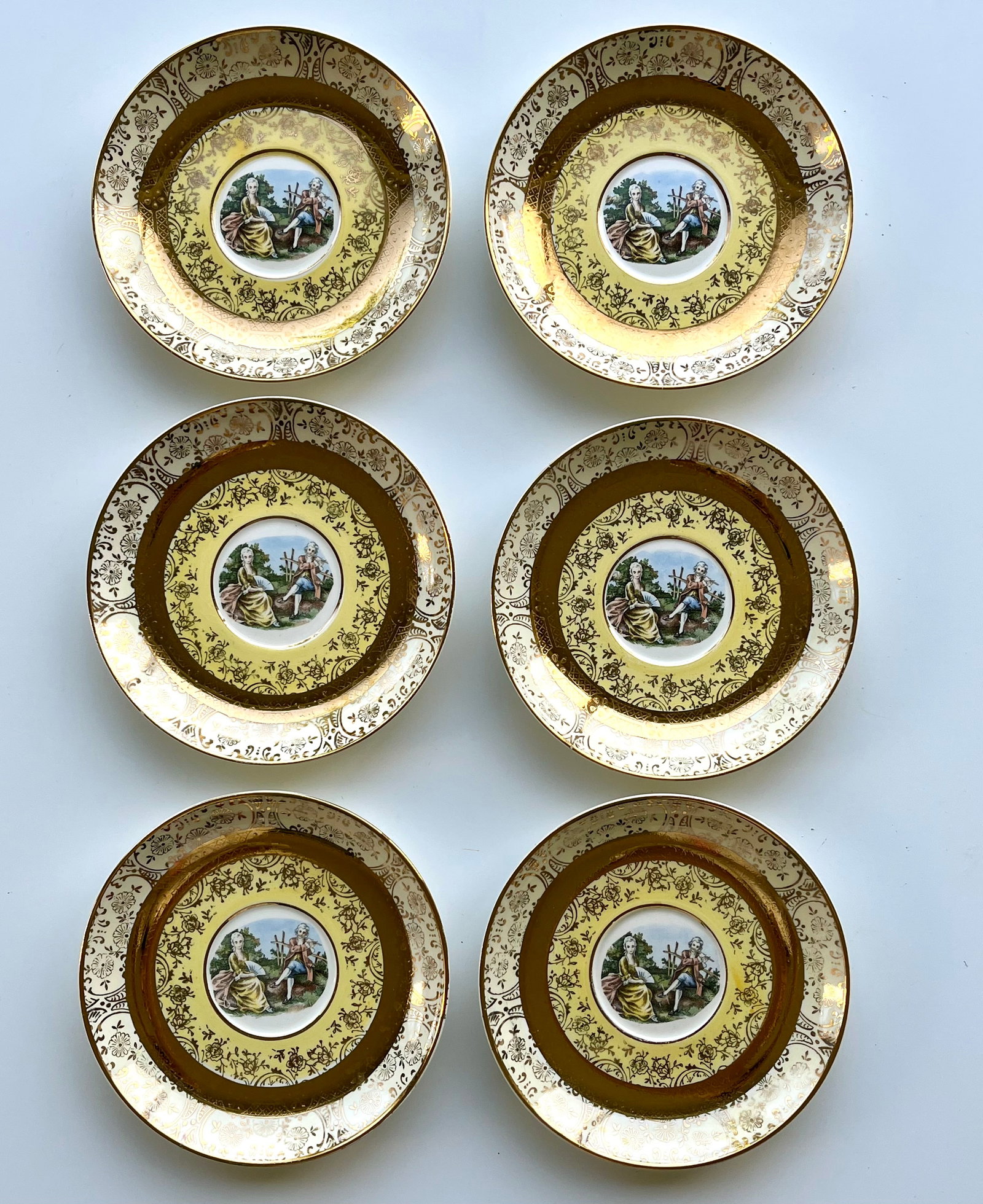 Victorian Style Porcelain Plates Set of 6 – 22K Gold Trim 5.5 inches Bromley: Set of 6 vintage Bromley decorative plates featuring a romantic courting couple scene in the center. Elegant ornate border with rich 22K gold trim. Marked on back: Bromley – Decorated – 22 Karat
