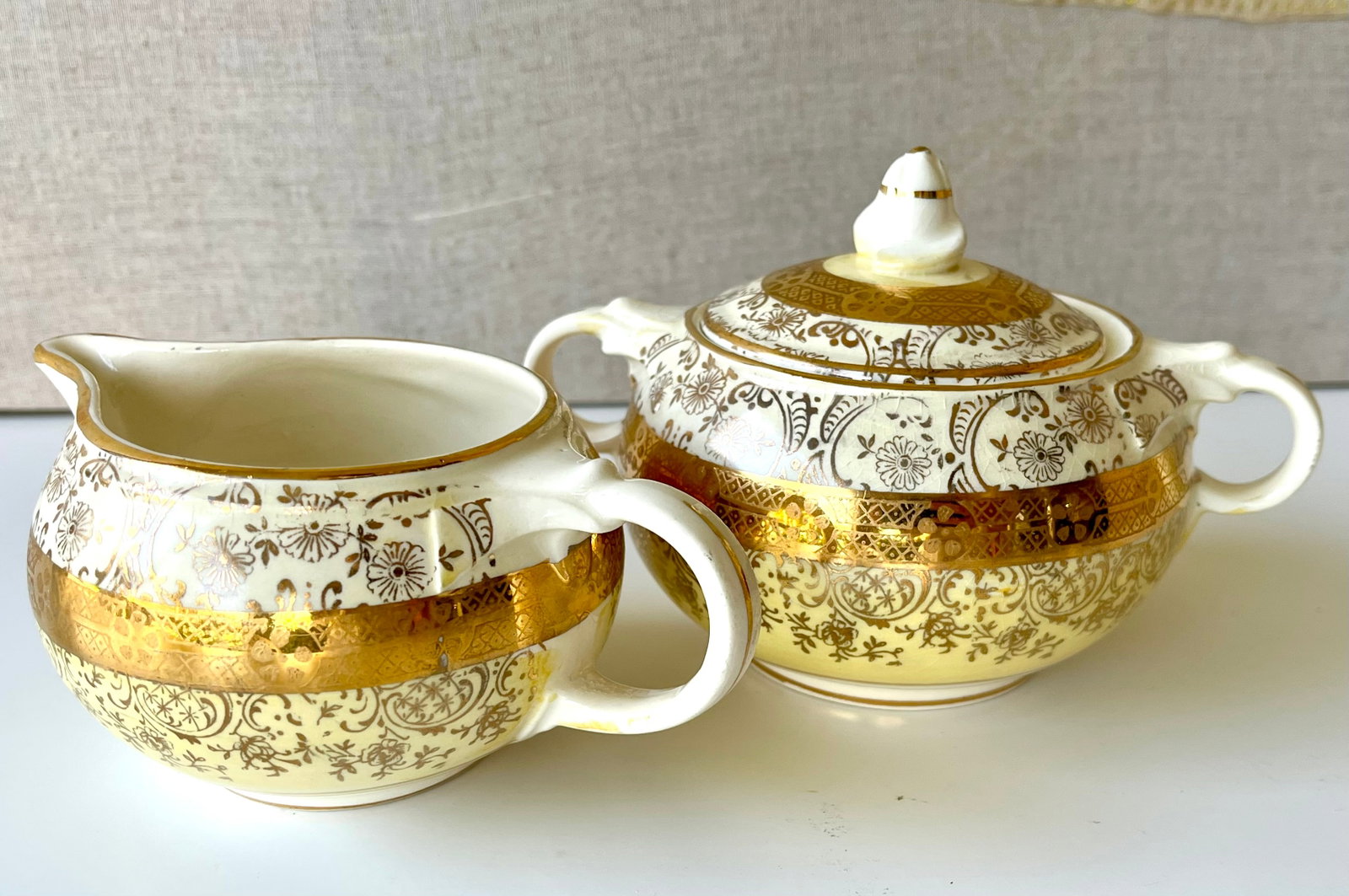 Victorian Style Creamer And Sugar Bowl Set Bromley – 22K Gold – Courting Scene: Beautiful vintage Bromley creamer and sugar bowl set with lid, featuring ornate 22K gold filigree and a charming romantic courting scene inside the creamer. Made of porcelain, with rich yellow glaze