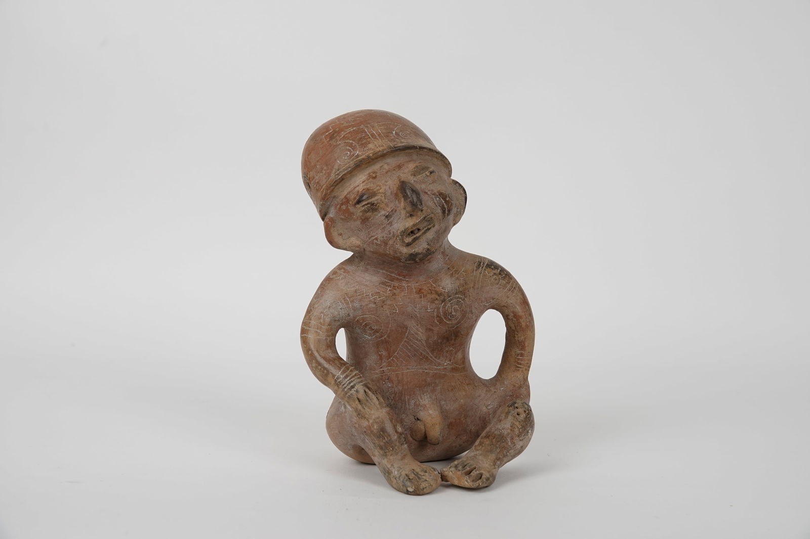 ARCHEOLOGIE: Statuette représentant un personnage assis, le visage grimaçant, les mains posées sur les genoux relevés.Céramique brun-rouge.Hauteur :Largeur :Culture Ganguala, caEquateur.Us