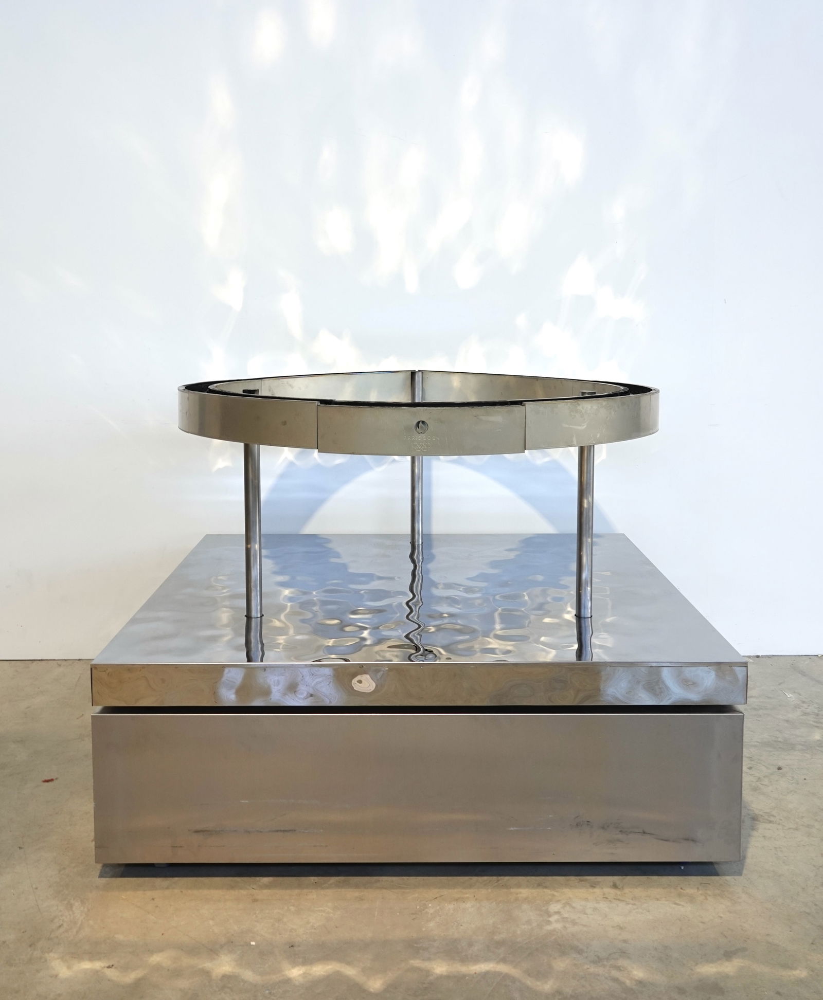Sport: Mathieu LEHANNEUR (born 1974)Relais de la Flamme cauldronSegmented metal circle inscribed with the Paris 2024 logo, on three legs resting on a base covered with hammered mirror-polished stainless stee