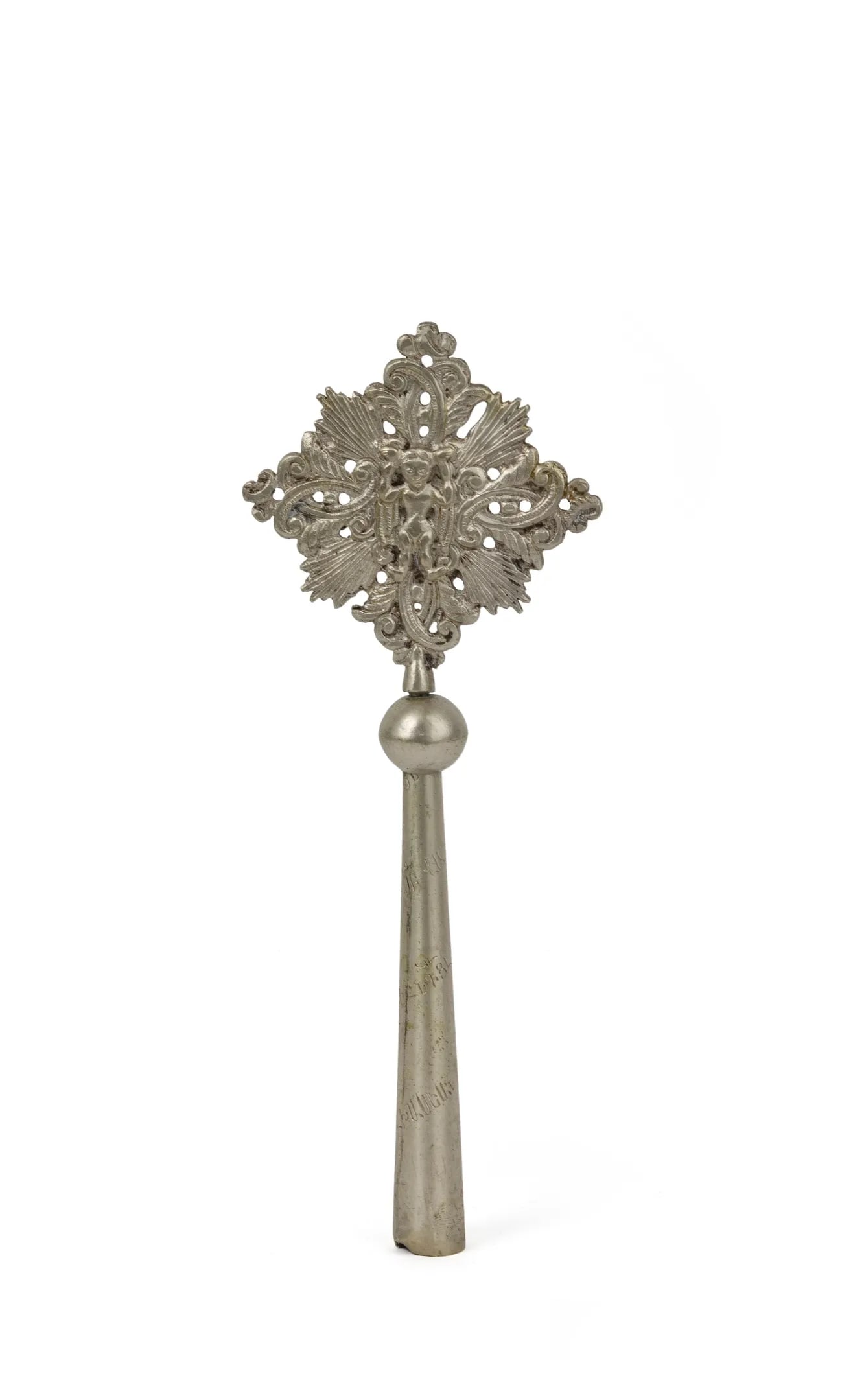Small silver blessing cross: Small silver blessing crossThe cross features an unusual design of stylized, curvilinear foliage around a figure probably representing the Christ Child. Along the sleeve, a spiral inscription in