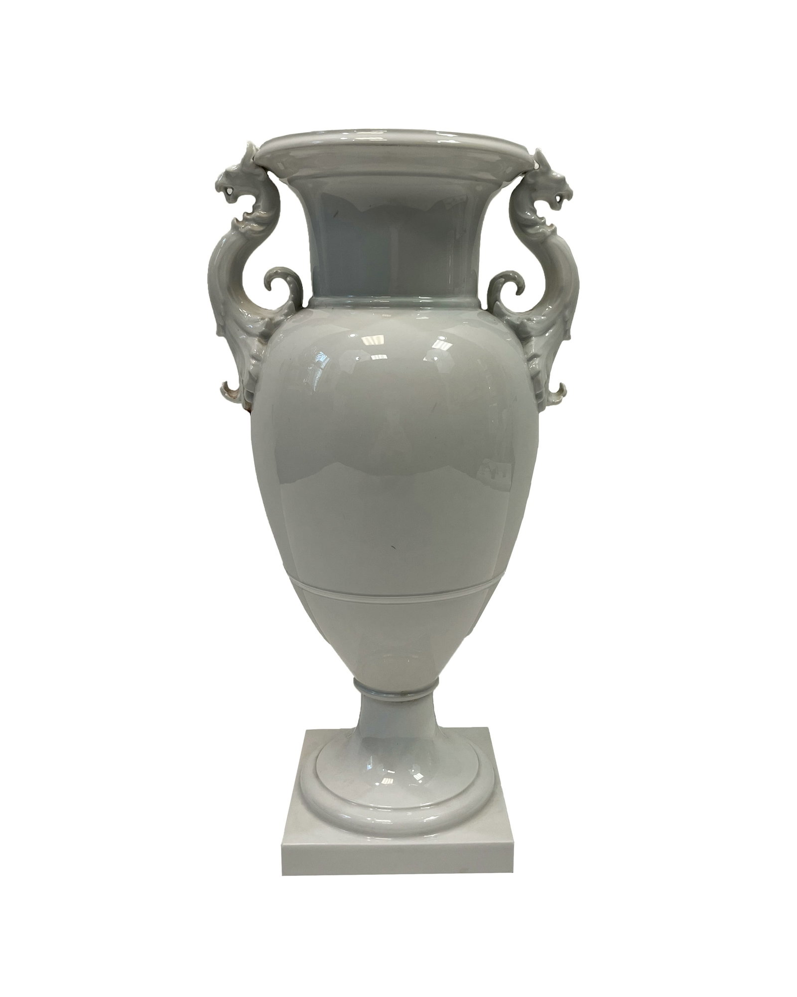 KPM Glazed White Porcelain Vase: One white porcelain vase with griffin handles, design by Karl Friedrich Schinkel (1781 - 1841). The vase has a traditional amphora shape and rests on an attached square base.All items sold as is and s