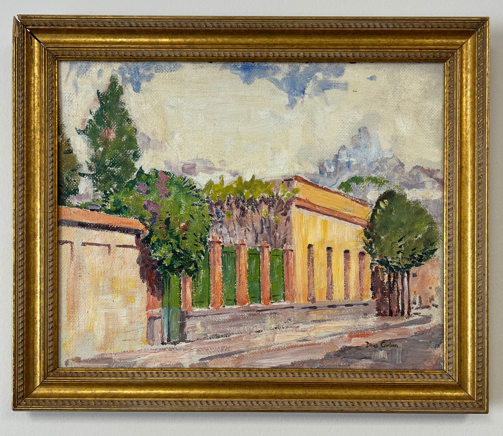 Dines Carlsen, "Street in Mexico", Signed Oil Painting: One signed oil on Masonite painting depicting a brightly colored street lined with buildings and trees. These buildings contain rounded arches and yellow walls with a wooden gate painted in red and gr