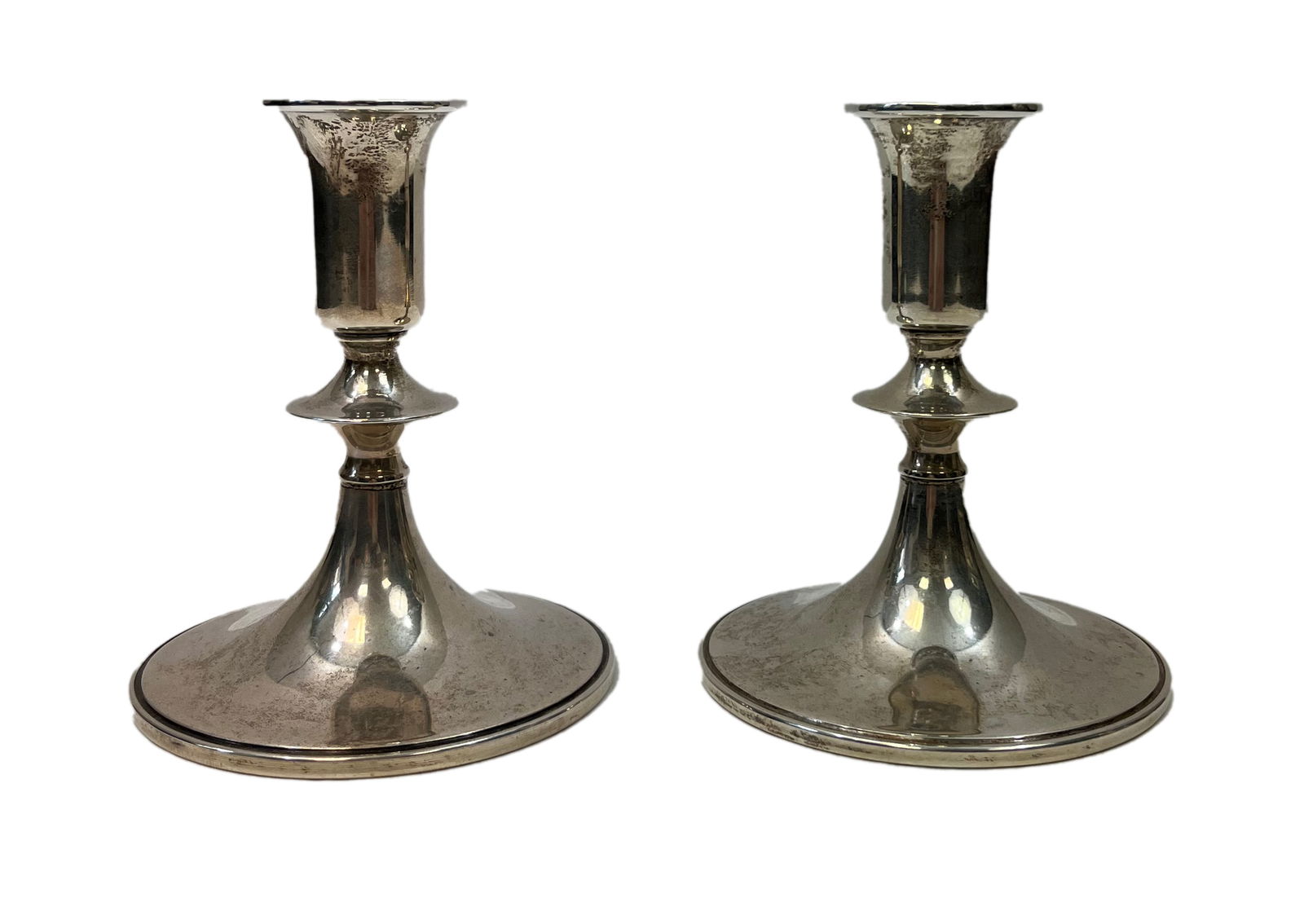 Pair of Cartier Sterling Silver Candlestick Holders: One pair of sterling silver Cartier candlestick holders. The items are stamped on the underside. Weight 476.6 grams.Each candlestick holder has a height of 5 in. and a width of 4 in.All items sold as
