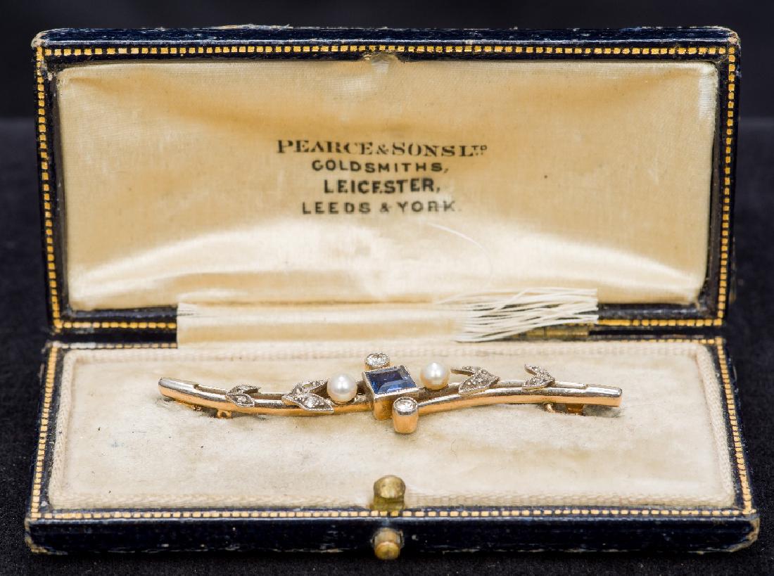 An Edwardian unmarked gold, sapphire, diamond and seed: An Edwardian unmarked gold, sapphire, diamond and seed pearl set bar brooch Of scrolling floral form, housed in original plush lined gilt tooled leather box, the lid inscribed. The brooch 5.5 cm wide.