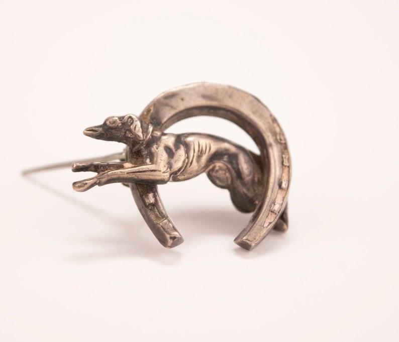 Silver Horse Shoe and Whippet Dog Brooch: Antique Victorian or Edwardian Silver Horse Shoe and Whippet Dog Brooch Pin. This whimsical, Victorian or Edwardian silver brooch depicting a running whippet or greyhound in a horse-shoe frame is good