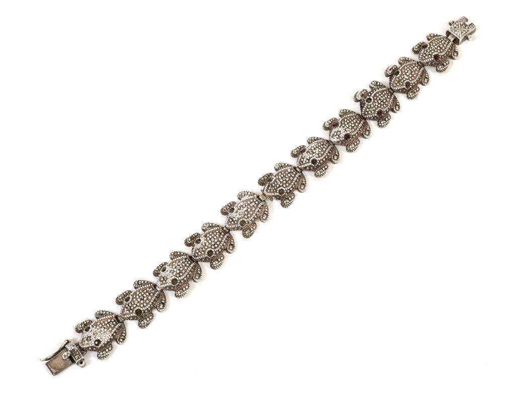Sterling & Marcasite Figural Frog Bracelet: Item/Description: Whimsical bracelet of frogs linked head to toe. Three dimensional design in Sterling Silver encrusted with marcasites. Two of the eleven are set with ruby eyes. Push-in box clasp wit