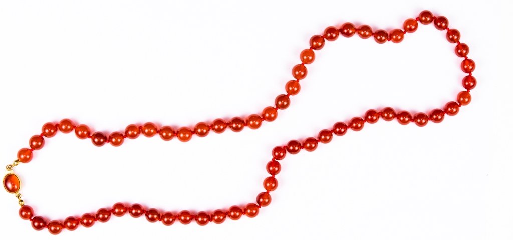 Vintage Signed Carnelian Bead Necklace: Item/Description: Luminous hand-knotted rope of carnelian beads. Deep orange. Cabochon accented gold-tone push-in clasp. Hallmarked on back of clasp: Luvoral in script. Material: Carnelian, silk, gold