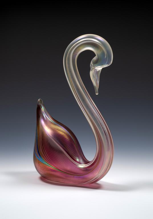 Stuart Abelman Pink Glass Swan Sculpture: Item/Description: Pink iridescent pulled feather art glass swan. Signed, numbered 1201-251 and dated at the base Material: Glass. Dimensions: Height: 7 3/4"; Width: 5". Condition: Minor surface wear. 