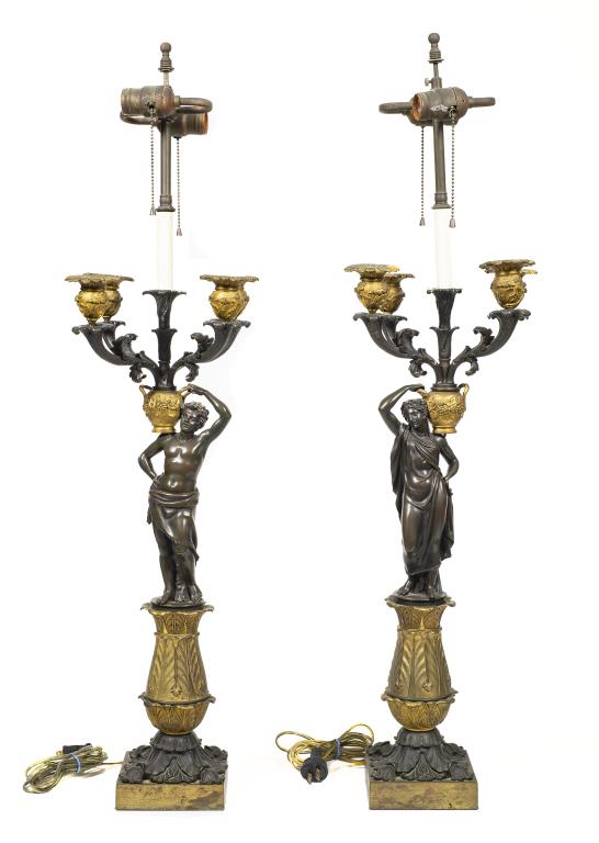 Dore Bronze Grecian Figural Table Lamps: Item/Description: Set of two 4-Arm, 2-Light ebonized bronze and gilt table candelabra as electrified lamps. Grecian figures holding urns. Material: N/A Dimensions: Base Length: 5"; Candelabra Width: 8