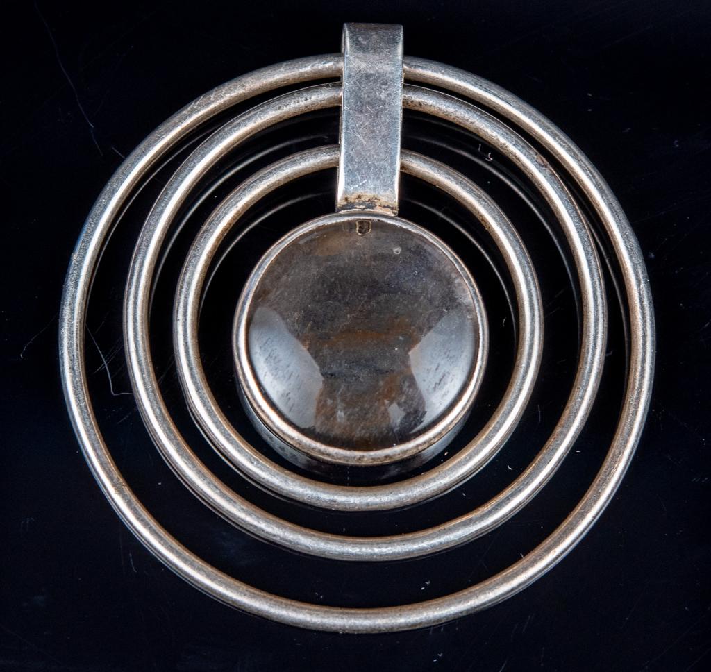 Modernist Sterling Labradorite Circles Pendant: Item/Description: Modernist Sterling Silver pendant of concentric circles with bezel set, glowing labradorite. Free-form, swinging. Soldered hanging clip. Hallmarked in part: RK, two animals, letter S