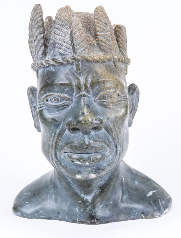 Gregory T. Madzivanzira Carved Steatite Bust: Item/Description: A signed Zimbabwean African carved green steatite bust of a tribal elder wearing a feathered crown by Gregory T. Madzivanzira. Artist incised signature and date on base: 1973. Materi
