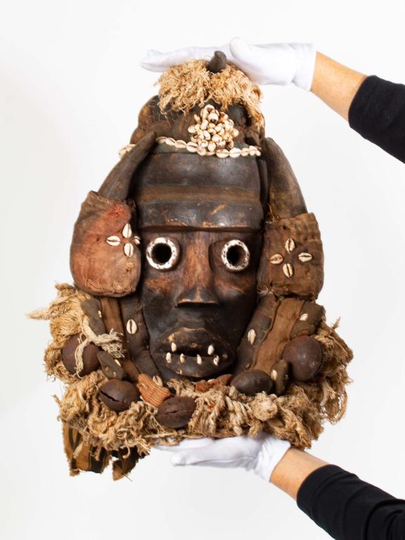 Dan Style Mask - Ivory Coast, Liberia: Item/Description: Highly ornate, decorative Dan style mask. Over the head hand carved wooden mask embellished with metal, cowrie shells, raffia, animal horn and teeth, bells, tradecloth with sewn on p