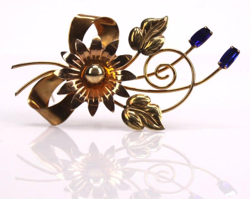 BAL-RON 12K Sapphire Glass Flower Brooch: Item/Description: Retro era Bal-Ron 12K Gold filled brooch. Artfully fashioned in tri-color yellow, green and rose gold as a stylized flower with leaves and stem tied with a ribbon bow embellished wit
