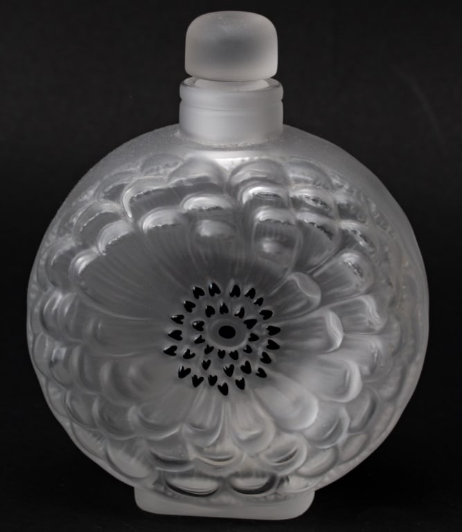 Lalique Dahlia Crystal Perfume Bottle: Item/Description: 'Dahlia' crystal perfume bottle with stopper depicting a flower with black center accents. Marked on the underside: Lalique France. Material: Crystal Dimensions: Length: 4 1/8"; Widt