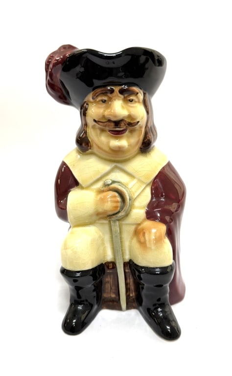 Shorter & Son Cavalier Soldier Figural Toby Jug: Item/Description: This Toby jug, marked at the bottom with Shorter & Son Ltd England, depicts a man with a knife, dressed in a red and white coat, with brown beard and hair. It is a hand-painted ceram