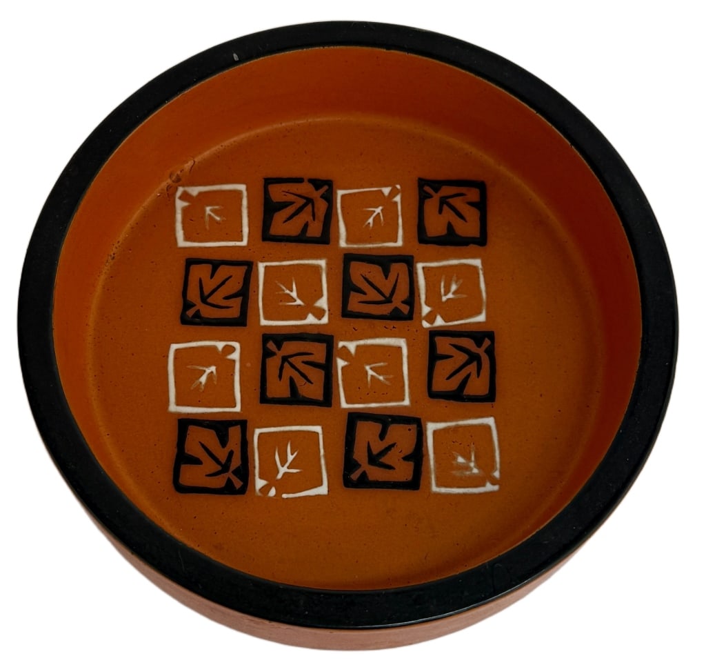 Danish Mid-Century Modern Shallow Dish: Item/Description: Mid-Century Modern round shallow ceramic bowl or dish featuring orange and black glaze finish. Checkered stylized leaf pattern in black and white to inside bottom. Partial paper