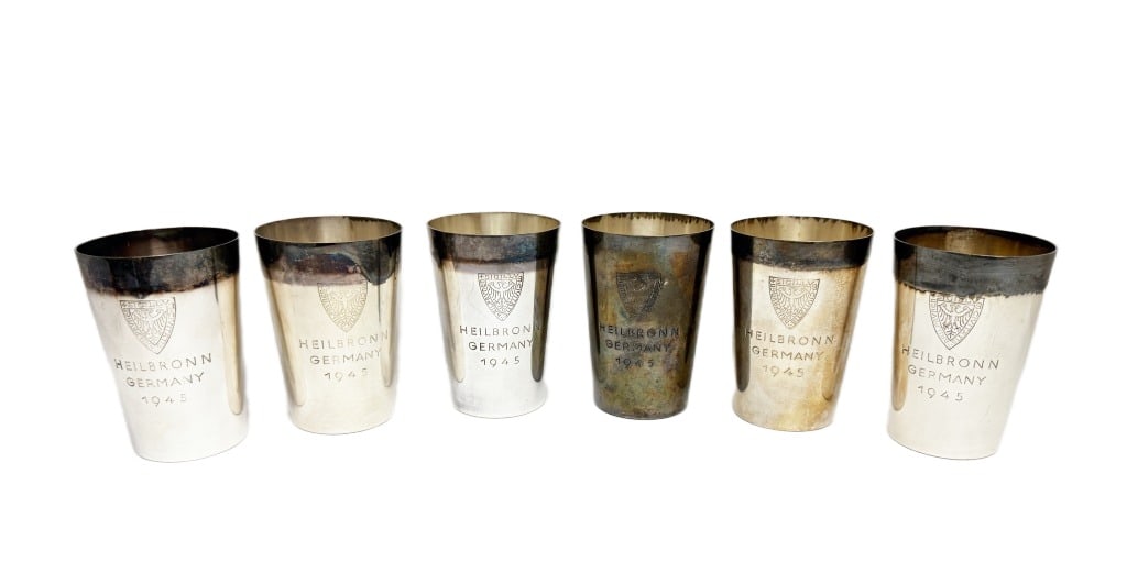 WWII Heilbronn Germany Silver-Plated Cups: Item/Description: World War II German silver-plated souvenir mementos cups dated 1945. Features six cups engraved with "HEILBRONN GERMANY 1945" and a crest. Heilbronn was a city in Germany that experi