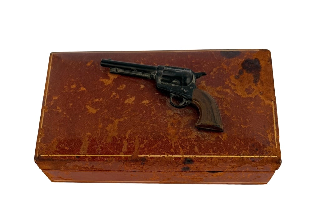 Western Novelty Miniature Revolver Vintage Box: Item/Description: Mid-century Old Western novelty cigarette box featuring a miniature die-cast metal revolver modeled after the iconic Colt .45 Single Action Army Peacemaker permanently mounted to the