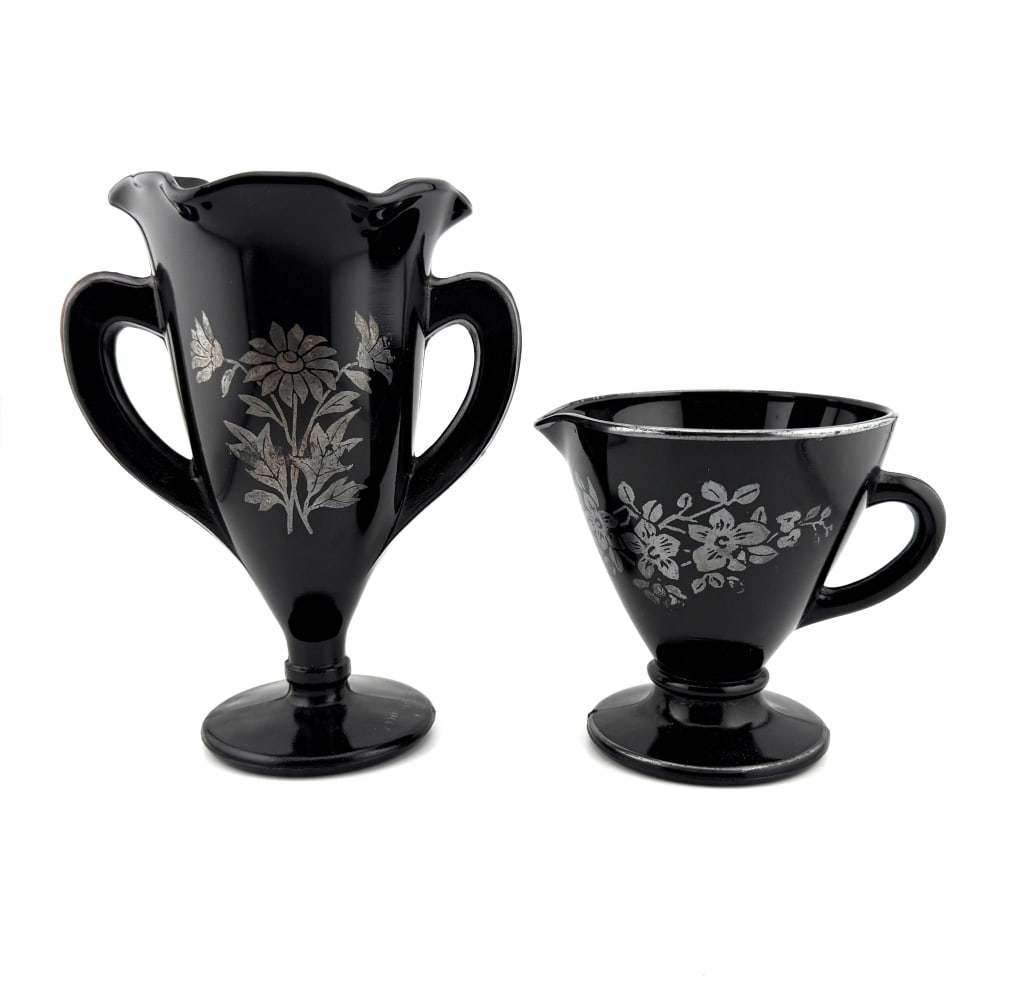 Art Deco Sterling Overlay Black Glass Cups: Item/Description: 1930s Art Deco creamer and loving cup. Black glass sterling silver overlay floral designs. Includes a two-handled loving cup / trophy vase and a handled creamer / small pitcher. No n