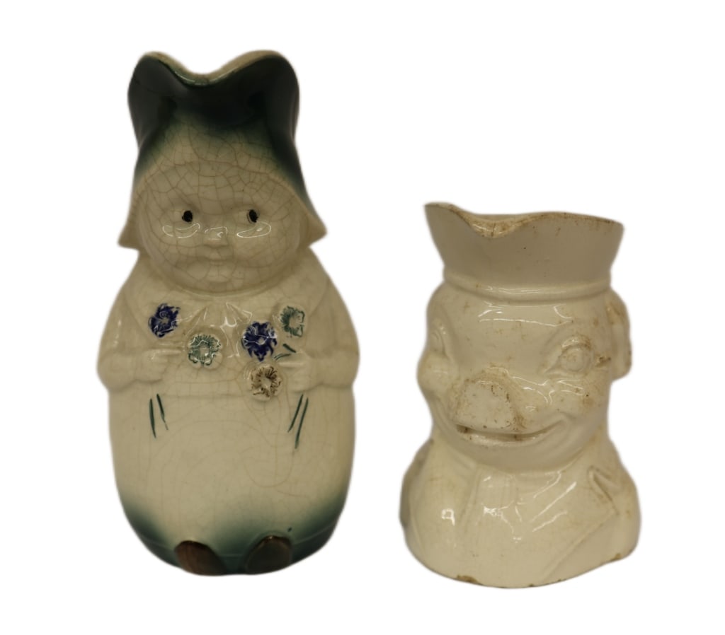 Two American Ceramic Character Pitchers: Item/Description: Pair of vintage figural ceramic pieces including a crackle-glazed Dutch Girl figural pitcher holding flowers and giving her distinctive "side-eye" expression. Also includes Colonial 