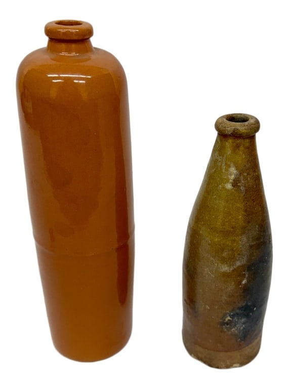 American Utilitarian Stoneware Bottles: Item/Description: Set of two American utilitarian stoneware bottles. One mid-20th century, glazed in a reddish-brown hue. Features a precise, uniform tooled collar rim, marked "USA" near the lower-rig