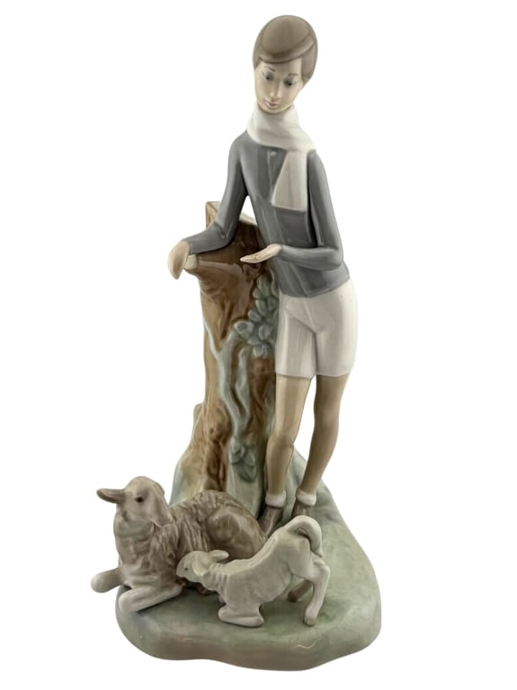 Lladro "Boy with Lambs" Porcelain Figurine: Item/Description: Lladro porcelain figurine "Boy with Lambs" (Model No. 4509), featuring a young shepherd in a gray sweater and white shorts posing with two small sheep. Designed by master sculptor