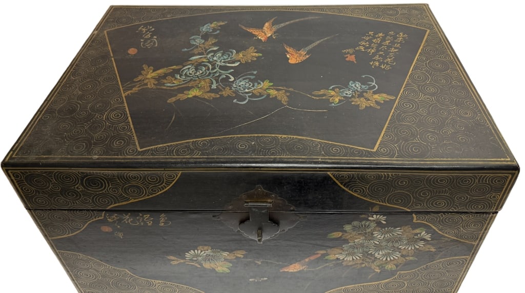 Chinoiserie Black Lacquer Chinese Chest: Item/Description: Antique black lacquer Chinese chest crafted from camphor wood, featuring traditional hand-painted bird and floral motifs framed by intricate gilt-painted "swirl" or cloud patterns. "