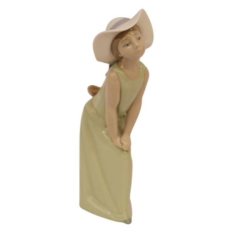Lladro "Curious Girl with Straw Hat" Figurine: Item/Description: Lladro "Curious Girl with Straw Hat" (5009) porcelain figurine, designed by Francisco Catal?. Issued in 1978 and retired from production in 2002. Figurine depicts a young girl in a m