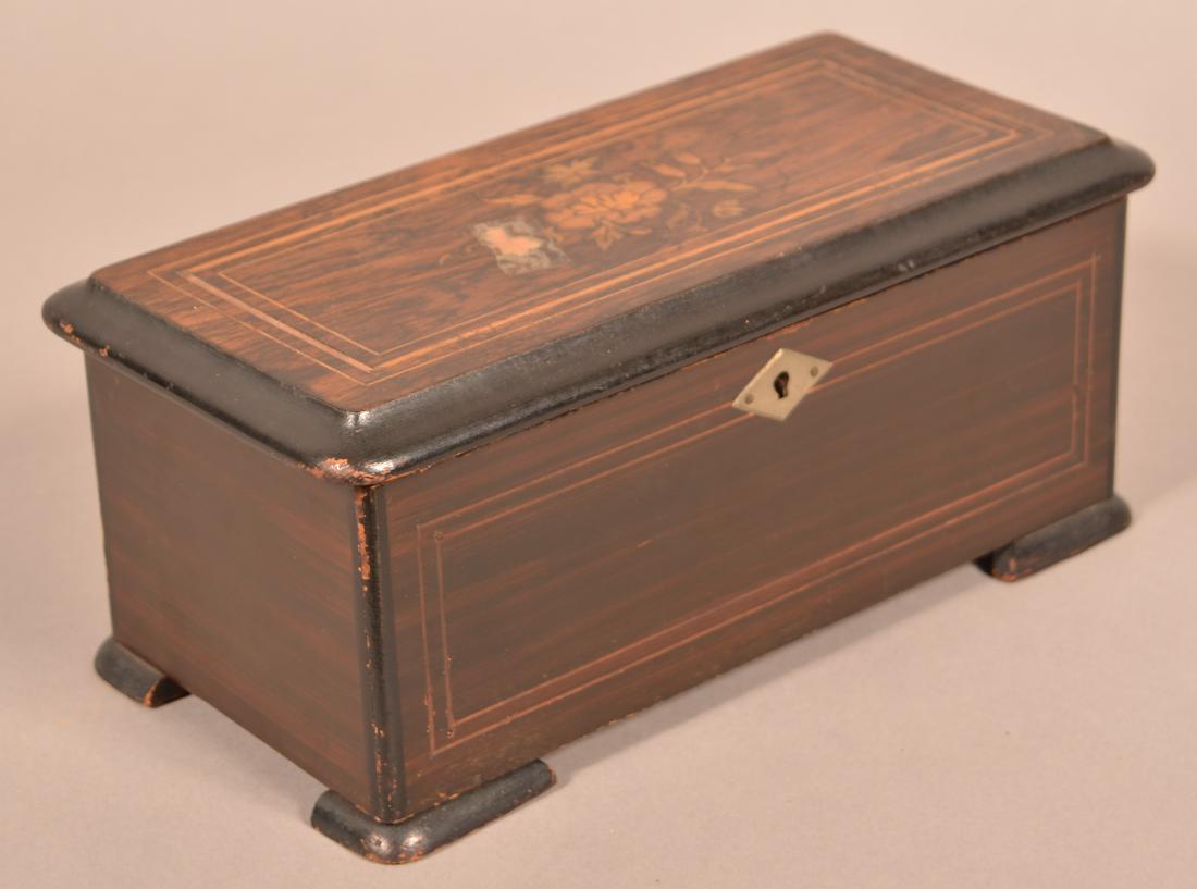 Small Antique Swiss Cylinder Music Box.: Small Antique Swiss Cylinder Music Box. Rosewood inlaid case. 5-1/4"h. x 12"w. x 6"d. Condition: Good with wear. Inlaid has loss. Mechanism is working with persuasion. One tooth missing on comb.