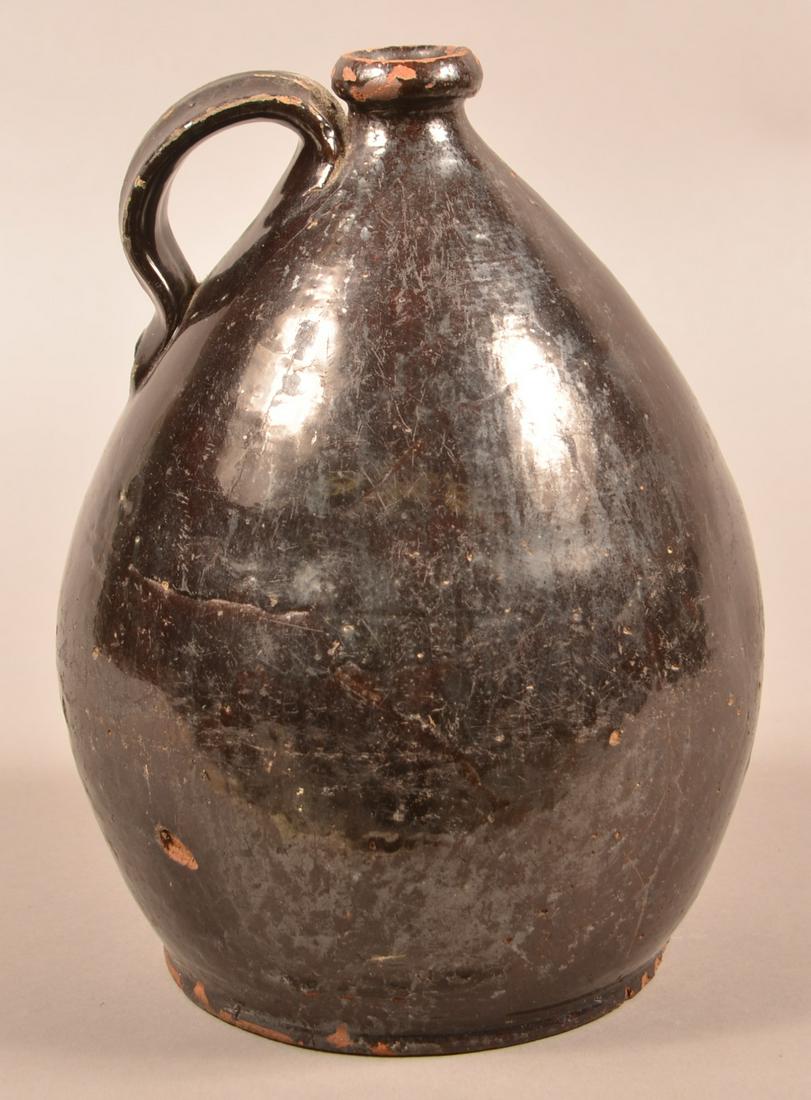19th Century Manganese Glazed Redware Jug.: 19th Century Manganese Glazed Redware Jug. Bulbous form with rounded lip and applied loop handle. 11-1/2"h. Condition: Good with small chips and wear.
