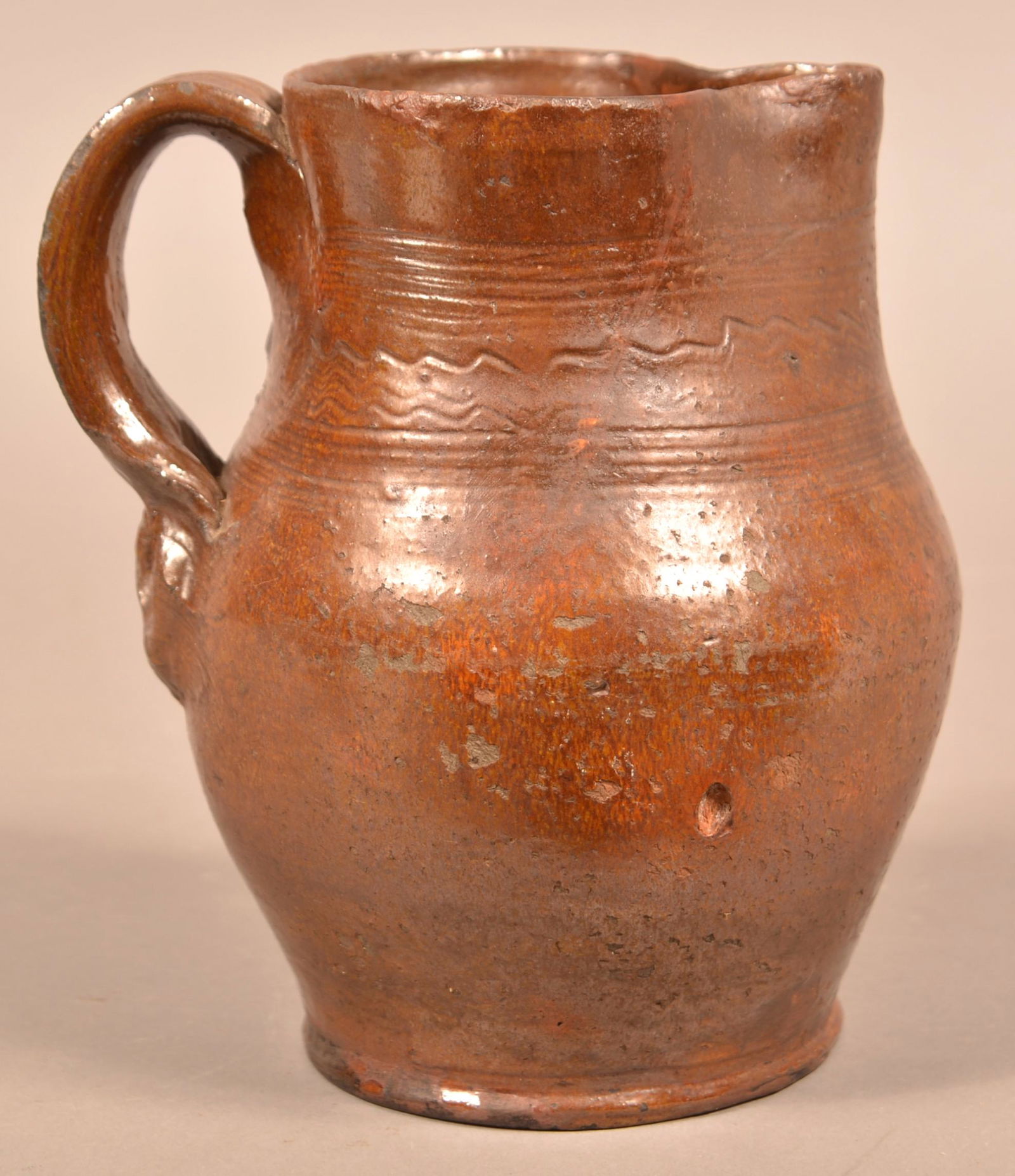 Glazed Redware Pitcher with Incised Decoration.: Glazed Redware Pitcher with Incised Decoration. Signed on bottom "HS". Attributed to Henry Schofield, Cecil County, MD, Circa. 1930. Bulbous body with applied strap handle. 8-1/4"h. Condition: Crack r