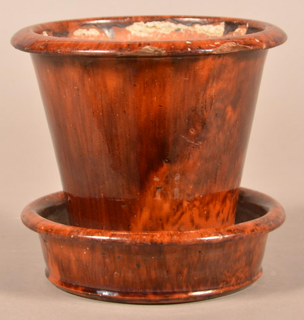 John Bell Mottle Glazed Redware Flower Pot.: John Bell Mottle Glazed Redware Flower Pot. Circa. 1850-1880. Attached saucer base, molded lip, tapered sides, stamped on bottom "John W. Bell, Waynesboro, PA". 6-1/4"h. x 6-3/4" diam. Condition: Good